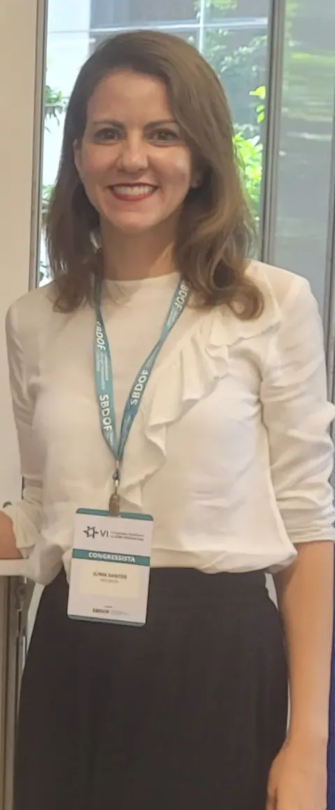 Dra. Júnia Santos ao lado da tela onde apresentou o trabalho no congresso
